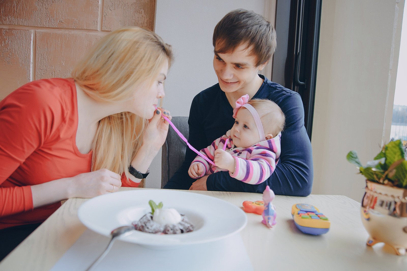 Mom Dad and their little daughter sitting in a cafe near the window